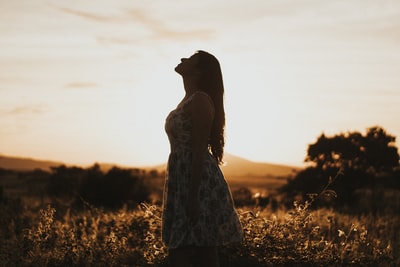 穿着花裙的女人站在棕色的草原上